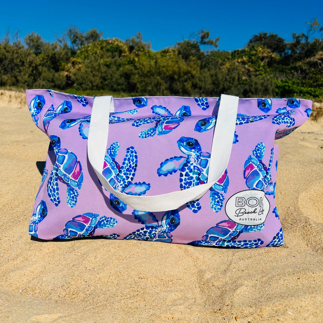 Purple Beach bag with a cute turtle pattern on a sandy beach