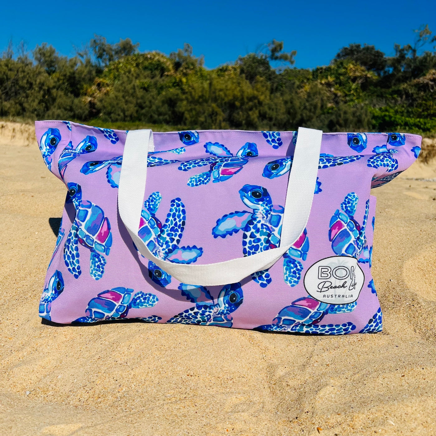 Purple Beach bag with a cute turtle pattern on a sandy beach