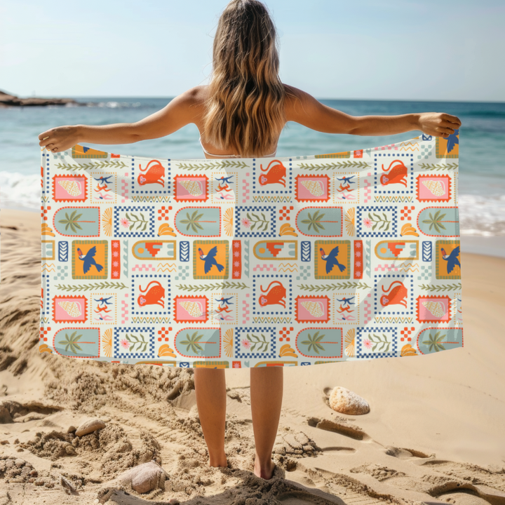 Person holding a colorful patterned sand free towel on a beach