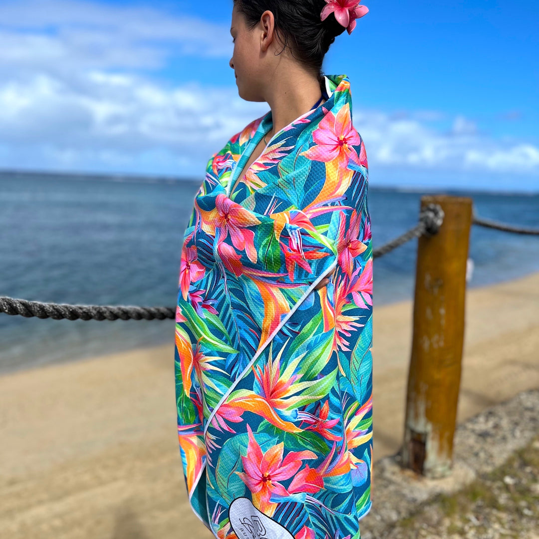 Girl wrapped in a colorful tropical birds of paradise flower patterned beach towel with ocean view
