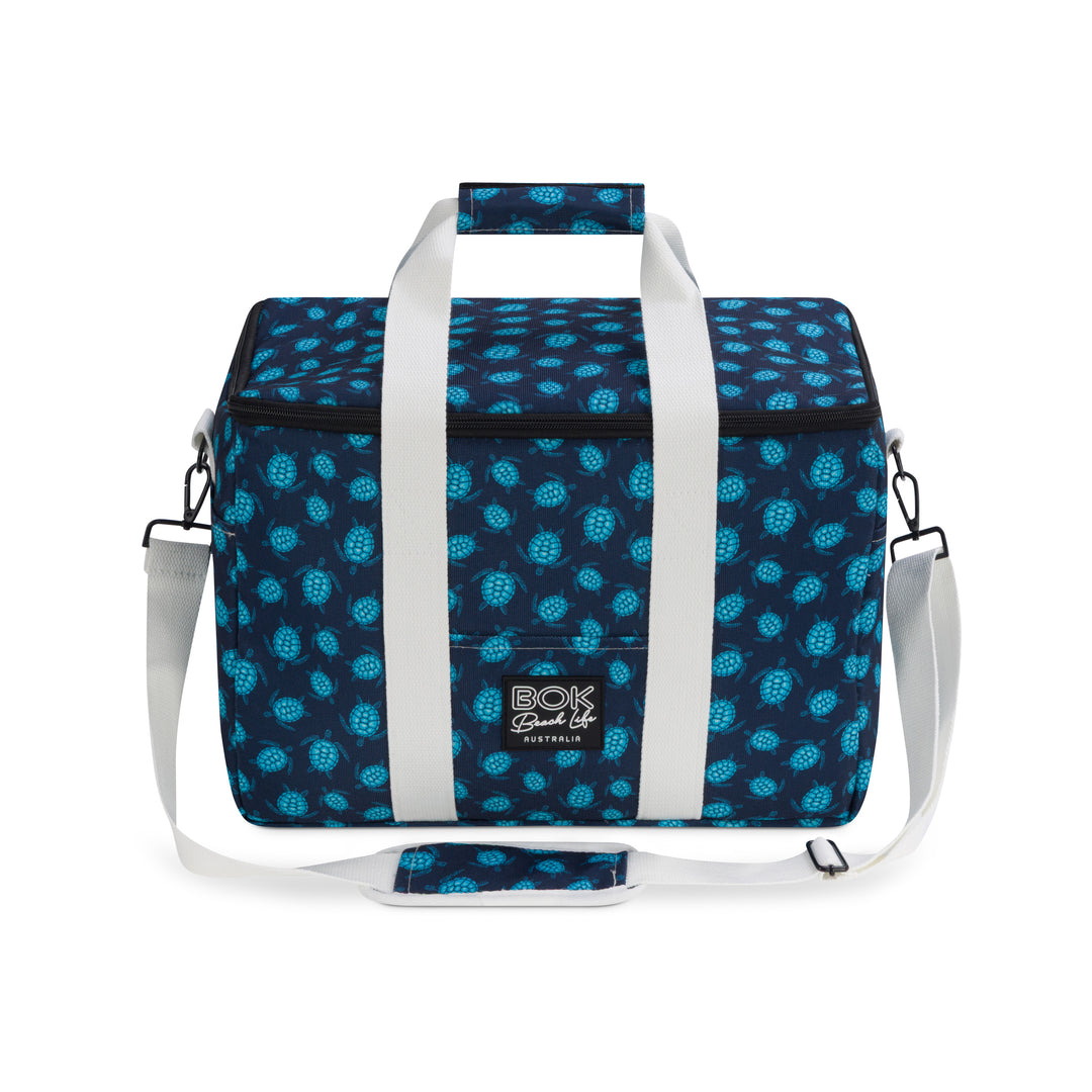 Blue turtle patterned cooler bag with white straps on a white background