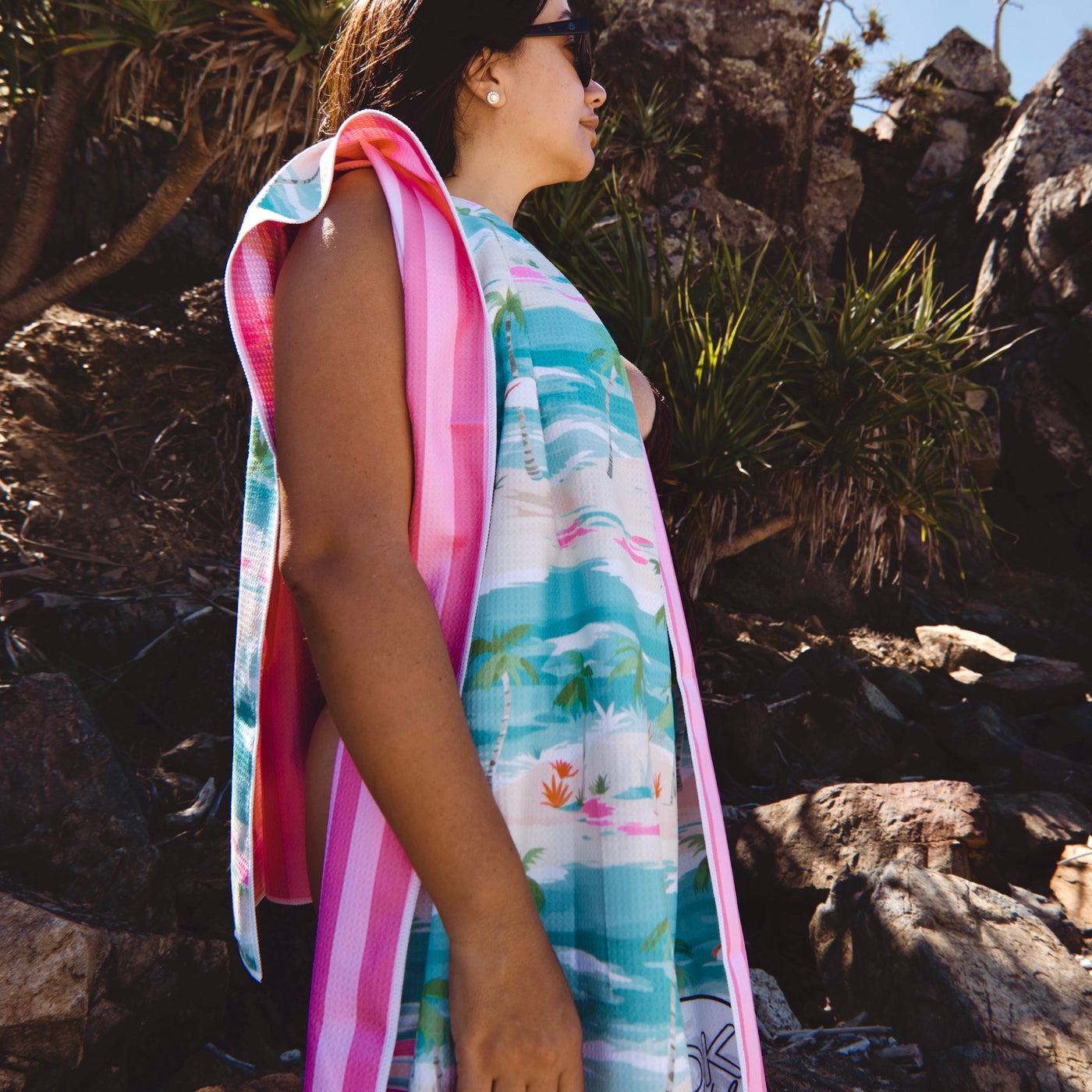 Woman with  a colorful beach towel over her shoulder in a rocky outdoor setting