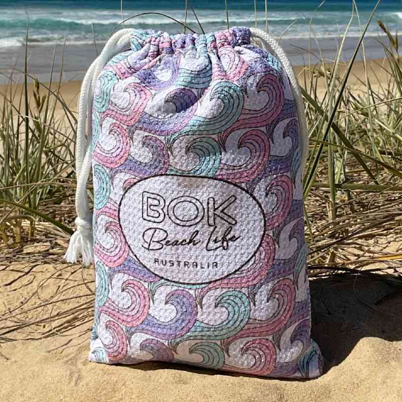 Bok Barrels Design Sand free beach towel in compact microfibre waffle fabric carry bag. Design features pink purple and teal waves.