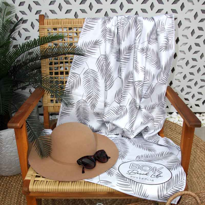 Coastal Luxe microfibre sand beach towel featured on a rattan chair.